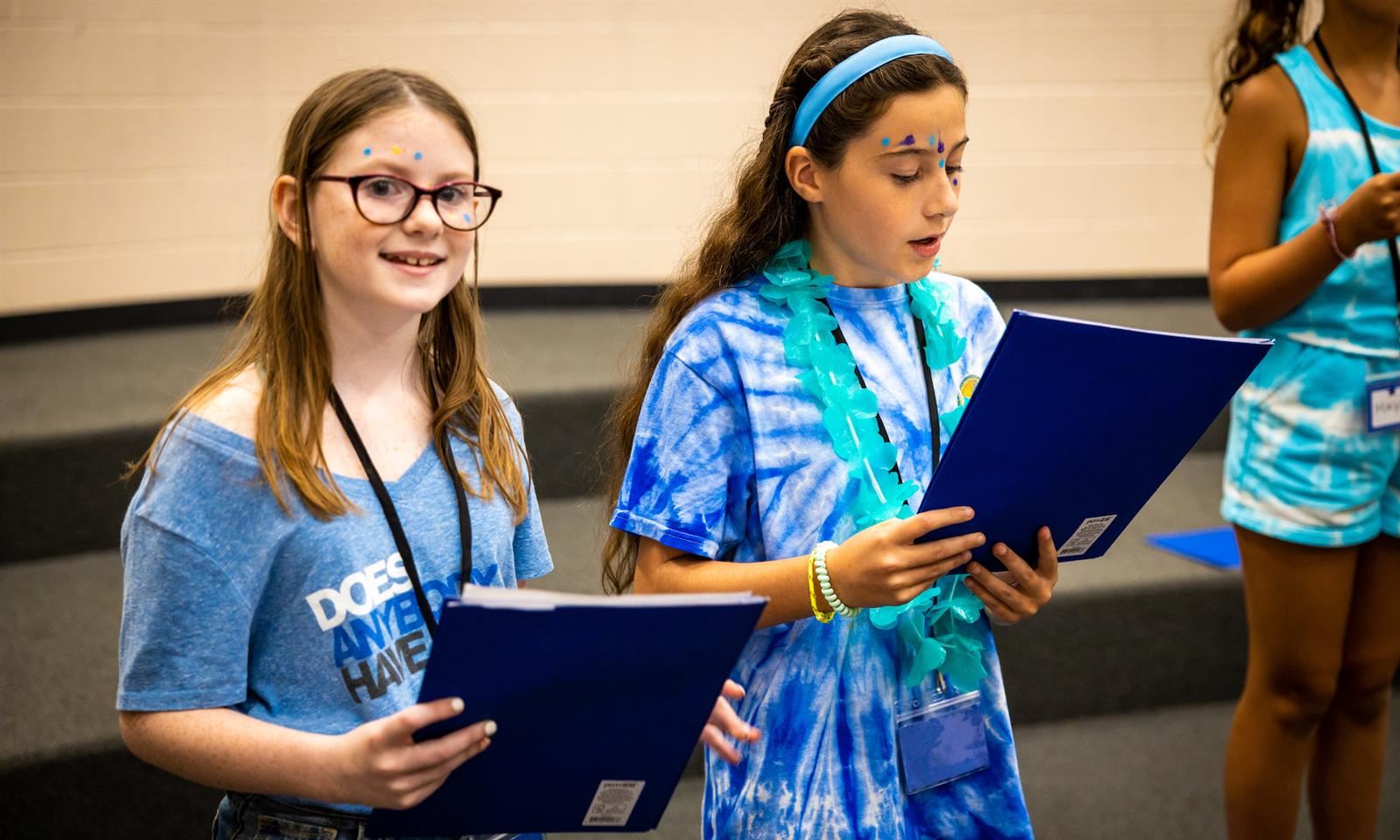 A girl smiles while holding a music book